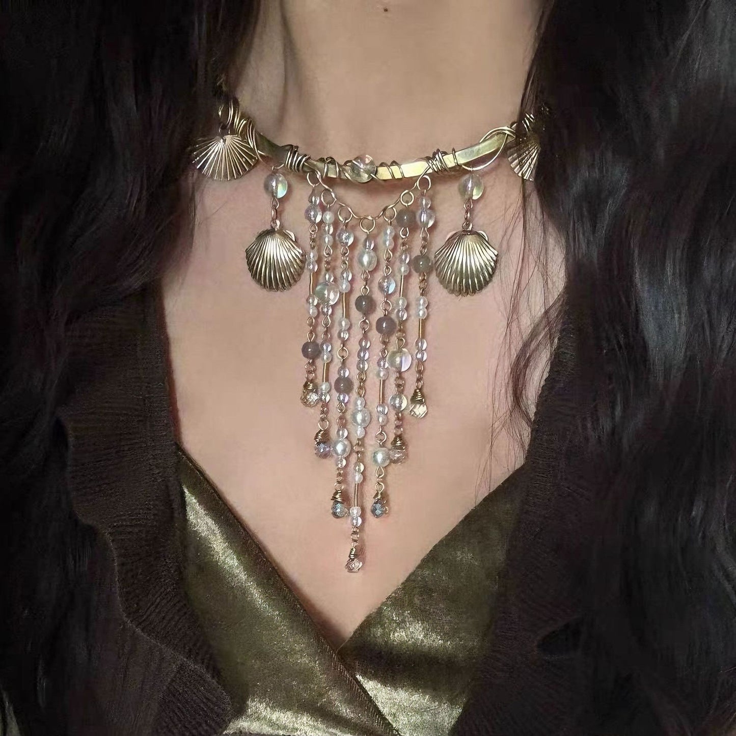 Necklace with shell and bead details on a person wearing a gold top.
