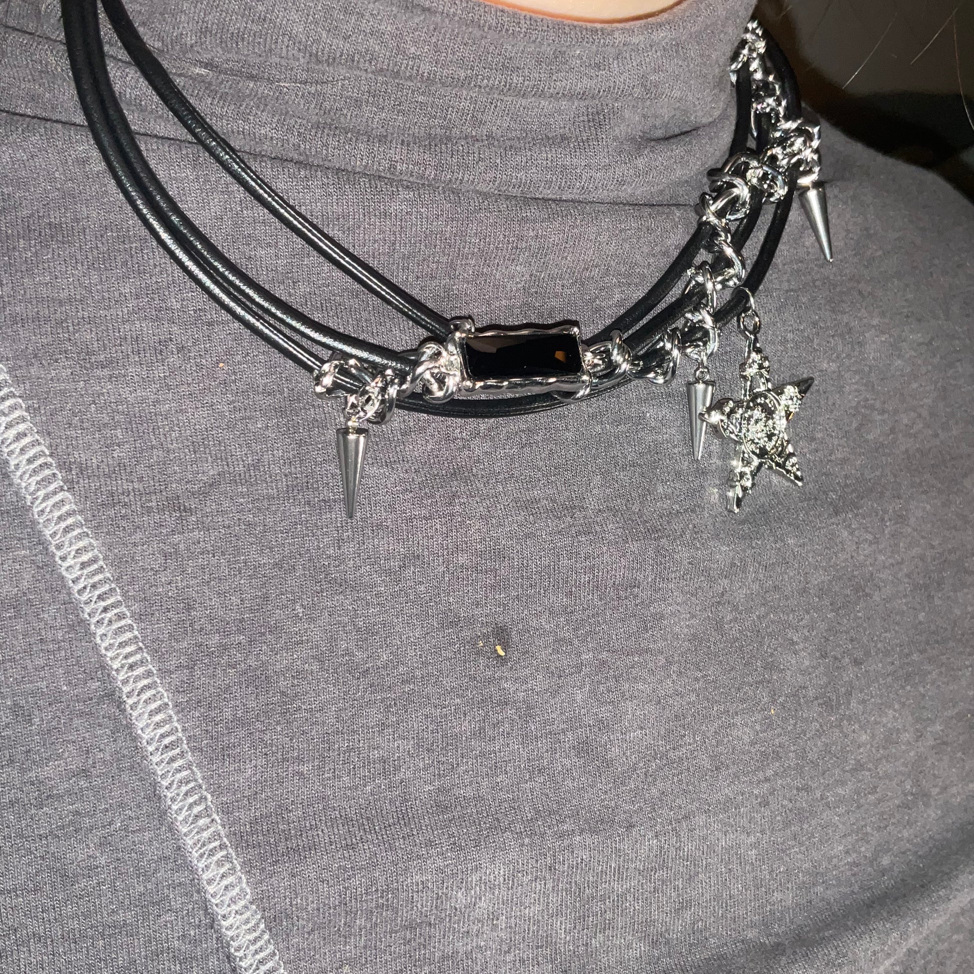 Necklace with star and spike charms on a gray shirt