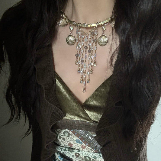 Person wearing a detailed necklace with a dark background